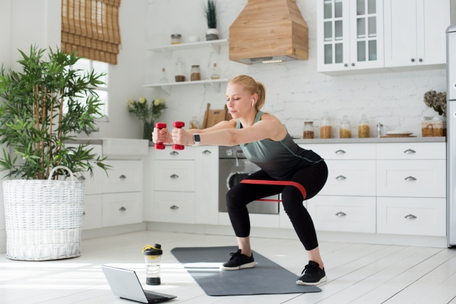 ダイエットのためにおもりを持ってスクワットをする女性の写真